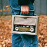 person in blue denim jeans and white socks standing on dried leaves during daytime